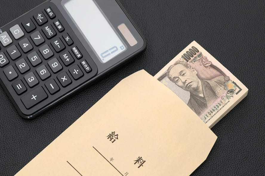 給料の封筒から出された1万円札と電卓